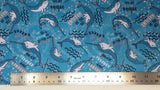 Flat swatch unique narwhal printed fabric in aqua (bright medium blue fabric with tossed blue cartoon narwhals and "Unicorn of the sea" "You are strange and wonderful" text, tossed white sea plants behind and pink/blue stars)