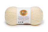 A ball of Lion Brand Touch of Alpaca yarn in cream shade on white background