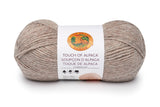 A ball of Lion Brand Touch of Alpaca yarn in cream taupe on white background