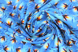Swirled swatch firefly printed fabric in fireflies (light/medium blue marbled fabric with blue shadow cattail plants and black/white lit fireflies with glowing yellow/orange lights)