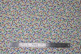 Flat swatch Tossed Tees fabric (white fabric with tossed golf tee posts allover in black, blue, green, yellow, red)