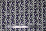 Flat swatch Screaming Skeletons fabric (purple fabric with repeated skeleton top halves holding their heads and screaming repeated striped pattern)