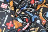 Swirled swatch doctor gadgets black fabric (black fabric with tossed full colour emblems: "Doctor is in" text, red hearts with beat, first aid sign, red plusses, brown leather bags, blood pressure cuffs, etc.)