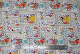 Flat swatch feed the bees fabric (light grey/white woven look fabric with vertical white rectangle labels/patches with pink, yellow, orange, purple, blue, green floral and tossed bees. Some labels have floral only, some have floral in light blue watering cans, some with yellow beehives)