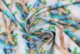 Swirled swatch sleeping koala fabric (white/light blue pale sky look fabric with light brown branches allover and sleeping grey/blue koalas wearing green and pink flower crowns, holding greenery)