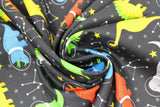 Swirled swatch space dinos fabric (black fabric with tossed grey and yellow and white stars and constellations with green, yellow, blue, orange, grey cartoon dinosaurs allover with astronaut helmets)