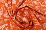 Swirled swatch halloween printed fabric in Skeletons on Orange (full skeletons, skulls, bones, and crossbones on orange)