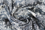 Swirled swatch halloween printed fabric in Ornate Skull Motif (white skulls and leaf like flowing design on black)