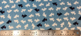 Flat swatch black and white scotty dogs fabric in blue (pale medium blue fabric with tossed scotty dog silhouettes in white, occasional black with red bandana)