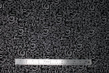 Flat swatch Silver Joy fabric (black fabric with collaged "JOY" text allover in silver metallic, text has many different fonts and sizes and goes both horizontally and vertically)