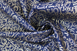 Swirled swatch Gold Joy fabric (black fabric with collaged "JOY" text allover in gold metallic, text has many different fonts and sizes and goes both horizontally and vertically)