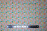 Flat swatch Seigaiha fabric (small scalloped shape fabric in white and rainbow colours with little faces in white spaces)