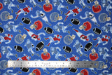 Flat swatch of football printed fabric on blue (medium blue fabric with tossed red and blue football helmets, brown footballs, small cartoon blue and red football players in various tackle/run positions)