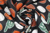 Swirled swatch of baseball print fabric on black (black fabric with tossed white baseballs, brown and orange baseball gloves, grey "#1" foam fingers)