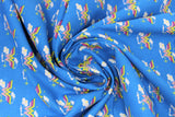 Swirled swatch licensed DC Comics printed fabric in Wonder Woman Cloud (yellow and pink W logo with small clouds on blue)