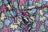 Swirled swatch licensed Harry Potter printed fabric in Mystical Houses (house animal drawings in bright multi colours on black)
