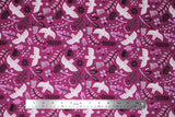 Flat swatch of Marabella fabric in summer plum (pale purple/magenta fabric with tossed emblems allover in white and dark purple: doves, assorted floral and greenery)