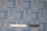 Flat swatch grey collage fabric (grey fabric with collaged horizontal and vertical text allover in white, light blue, and dark blue. Canadian themed words and phrases "Canadian Capers" "Hockey Hero" "Cool" etc.)