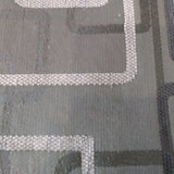 Woven jacquard upholstery fabric in mid grey with the outlines of overlapping rounded rectangles in dark greys and light grey