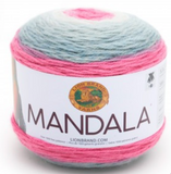 A cake of Lion Brand Mandala yarn in colourway unicorn (white, light to medium greys, bright bubblegum pink)