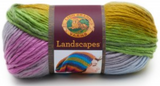 A ball of Lion Brand Landscapes yarn on white background in colourway wild flower (grey, pale blue, pale purple/pink, green, dark yellow/gold)