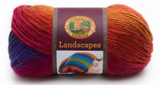 A ball of Lion Brand Landscapes yarn on white background in colourway volcano (orange, red, fuchsia, dark blue)