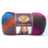 A ball of Lion Brand Landscapes yarn on white background in colourway tropics (orange, purple, fuchsia, olive, grey, blue)