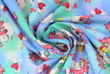 Swirled swatch magical themed printed fabric in print unicorns (sky blue and light green marbled fabric with white cartoon unicorns with pink manes/tails standing on mini cloud platforms with 1/4 rainbows, tossed white and pink hearts)