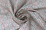 Swirled swatch Love is Patient fabric (white fabric with love related text allover in small cursive lettering black and red)