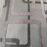 Woven jacquard upholstery fabric in light grey with the outlines of overlapping rounded rectangles in dark grey, white, and light grey