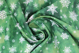 Swirled swatch of snowflake printed fabric in green (green marbled look fabric with white tossed snowflakes in various sizes and styles)