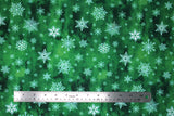Flat swatch of snowflake printed fabric in green (green marbled look fabric with white tossed snowflakes in various sizes and styles)