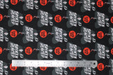 Flat swatch broken hearted fabric (black fabric with Cruella De Vil cartoon graphics repeated in black cloak with "BROKEN HEARTED" in white lettering across, red circular badges with black "Cruella De Vil" text)