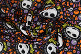 Swirled swatch frightful halloween fabric (black fabric with tiny tossed orange and purple halloween emblems allover: ghosts, jack-o-lanterns, brooms, crosses, etc. with medium sized Jack Skellington heads with "Master Fright" text in yellow)