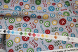 Raw hem swatch vroom vroom fabric (grey fabric with tossed colourful wheels in various sizes/styles: red, green, blue, yellow, orange. "Vroom vroom" text, "honk honk" text, etc.)