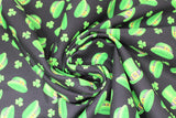 Swirled swatch St. Patrick's Day themed fabric in green hats and shamrocks tossed on black
