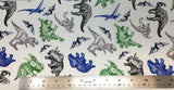 Flat swatch cretaceous dinosaurs printed fabric in white (white fabric with tossed assorted dinosaurs from the cretaceous period in grey, black, blue, green colours and tossed small mountains/volcanos)