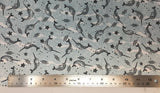 Flat swatch narwhal printed fabric in blue (pale blue and white pebble/water texture print background with tossed drawn narwhals, starfish, and wave lines in black)