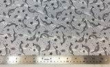 Flat swatch narwhal printed fabric in purple (pale purple and white pebble/water texture print background with tossed drawn narwhals, starfish, and wave lines in black)