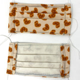 Front and back view of mask with white elastic ear loops (beige mask with tossed brown plaid look hearts with white stitching around)