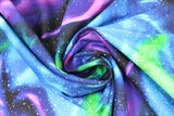 Swirled swatch dancing sky fabric (black fabric with large organic shaped light paths in blue, purple, green, and white star dots)