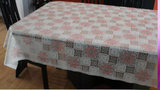 Square photo clear vinyl tablecloth draped over table (white/brown checkered quilt squares pattern with orange flower heads tossed)