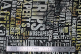 Flat swatch journey themed fabric in large script (dark grey watercolour marbled fabric with white/yellow marbled look assorted size text with travel keywords "Trips" "Encounter" etc)