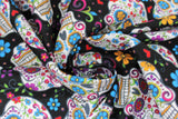Swirled swatch black fabric (black fabric with medium sized tossed sugar skull heads with colourful decorative floral and swirly designs allover in blue, orange, red, green, purple, etc. with tossed floral)