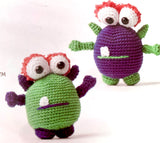 Completed Amigurumi monsters (green with purple/pink accents, purple with green/pink accents)