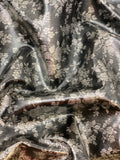 Crinkled swatch of dark grey velour fabric with light grey floral pattern allover (leather look)