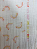 Raw hem swatch double gauze fabric with small faint rainbows on white