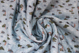 Swirled swatch winter flannel in trees on blue (light blue fabric with blue cross stitch pattern and tossed tiny green trees and dotted direction lines allover)