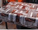Rustic (wooden spoons and slotted spoons laid on weathered boards at horizontal and vertical angles with occasional wording such as "Tradition" and "Wood" superimposed on boards) opaque vinyl draped over a dining room table with matching chairs around it.