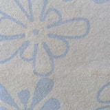 Swatch of light blue flannel fabric printed with slightly darker blue 'groovy' flowers that somewhat resemble amoebas.